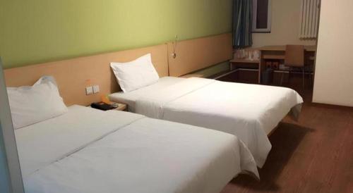 two beds in a hotel room with white sheets at 7 Days Inn West Gate of Taiyuan University of Technology in Taiyuan