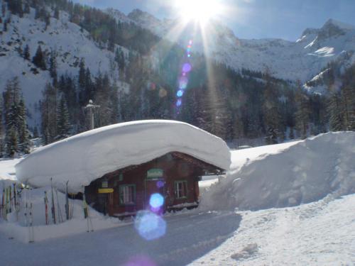 a small building covered in snow with the sun in the background at Alpengasthof Gern Alm in Pertisau