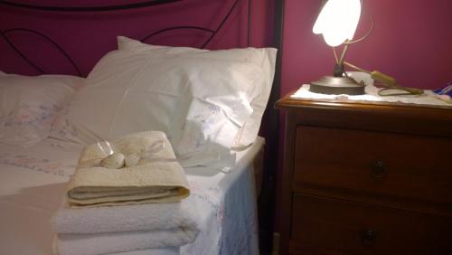 a bed with towels and a lamp on a night stand at B&B Villa Romina in San Cataldo