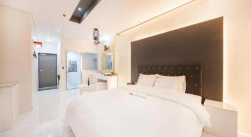 a bedroom with a large white bed and a bathroom at SH Hotel in Mokpo