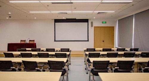 an empty classroom with tables and chairs and a whiteboard at Liyuan Hotel in Shenzhen