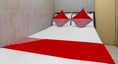 a red and white bed with red pillows on it at Hotel O Benteng Kost in Jambi