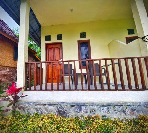 a house with a balcony with two doors and chairs at Pondok rinjani bungalow tetebatu in Tetebatu