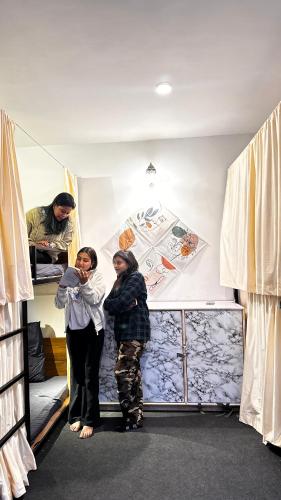 two women are standing in a bunk bed at La Hostelgia in Manāli