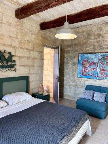 a bedroom with a blue bed and a blue couch at Ta Skorba Farmhouse Mgarr in Mġarr