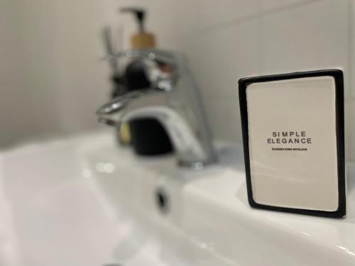 a sign on a sink with a sink faucet at Atlas suites WEST in Košice