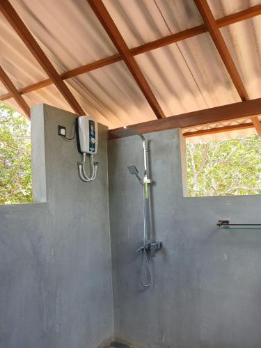 a bathroom with a shower and a television on the wall at Chena Hut Habarana in Habarana