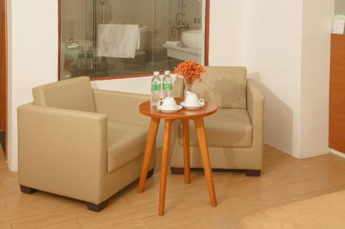 a living room with a chair and a table at Gardenia Hue Hotel in Hue