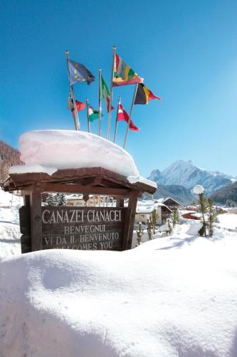 Un cartello nella neve con le bandiere sopra. di Hotel il Caminetto Sport a Canazei