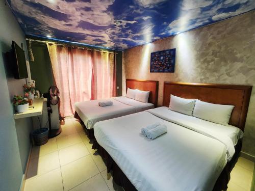 two beds in a hotel room with a painting on the ceiling at Boutique Hote123 in Kuala Lumpur