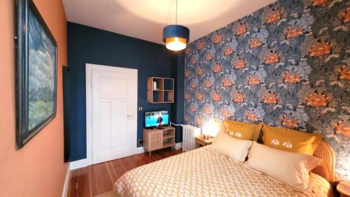 a bedroom with a bed with a floral accent wall at Le Jardin des Roses - parking gratuit dans la rue - gare à 500 m in Saverne