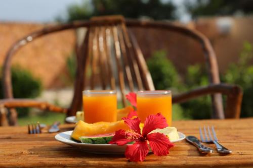 a table with a plate of fruit and two glasses of orange juice at Kigwedeni Villas in Nungwi