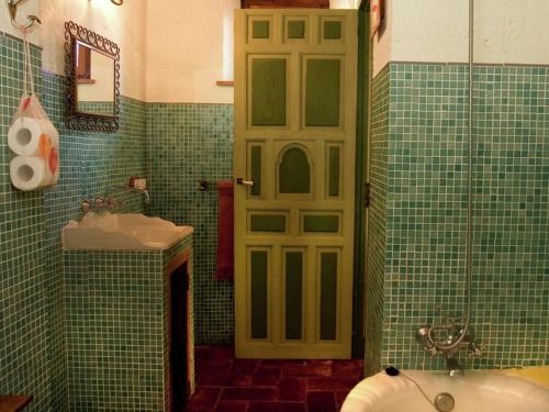 a green tiled bathroom with a toilet and a sink at Charming Stone Cottage in Alájar