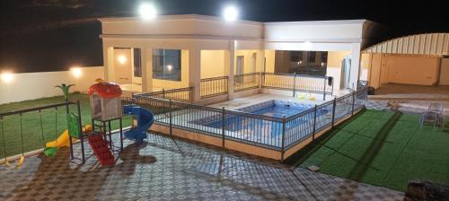 a man standing in front of a house with a swimming pool at Ain almasfa house بيت عين المسفاة in Al Ḩamrāʼ