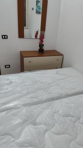 a bed with a white comforter and a dresser at Mazzeo in Santa Maria di Castellabate