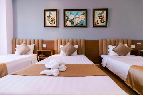 a room with two beds with a teddy bear sitting on the bed at Gardenia Hue Hotel in Hue