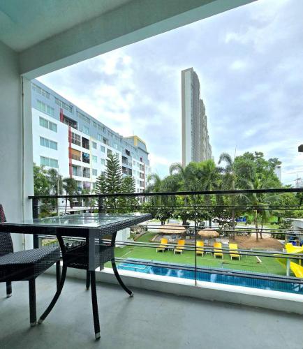 a balcony with a table and chairs and a pool at The Regizt Jomtien Pattaya in Jomtien Beach
