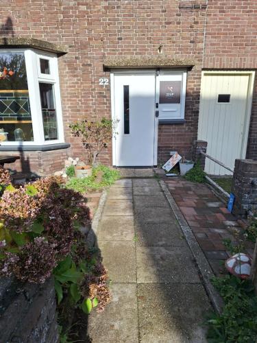 a white door on a brick house with a sidewalk at 22up Bed & Koffie in Den Burg