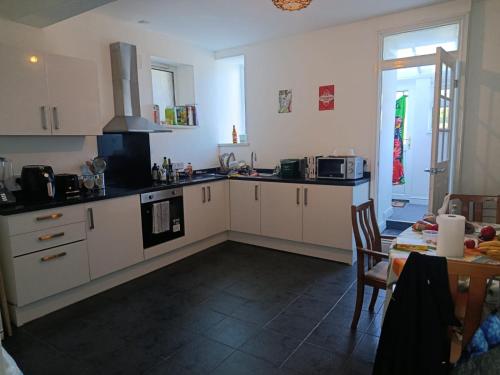 a kitchen with white cabinets and a table and a dining room at Miskin in Llwyn-y-pia
