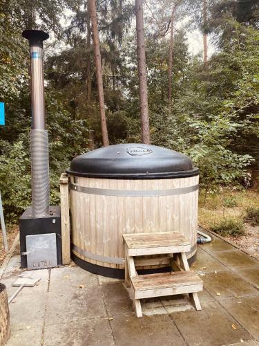 a wooden hot tub with a bench and a stove at Bosrijk Tiny House op de Veluwe in Beekbergen