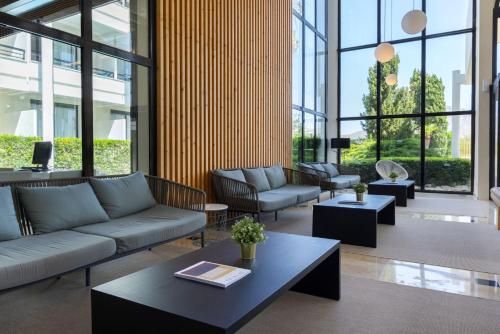 a living room with couches and tables and windows at Hotel Bahia Pollensa in Port de Pollensa