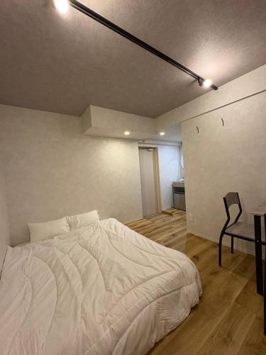 a bedroom with a white bed and a chair at Simple Hotel Tenjin Fukuoka in Fukuoka