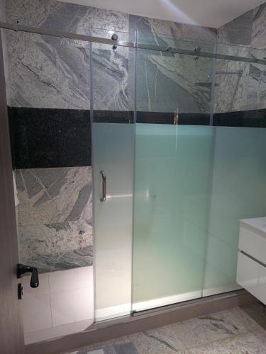 a shower with a glass door in a bathroom at The Iconic Place in Garki