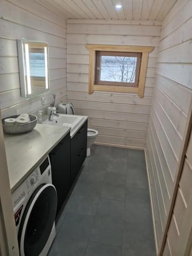 a bathroom with a sink and a washing machine at Villa Hackberry Hill in Rovaniemi
