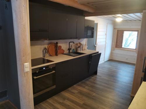 a kitchen with black cabinets and a wooden floor at Villa Hackberry Hill in Rovaniemi