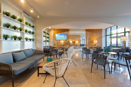 a restaurant with a couch and tables and chairs at Hotel Bahia Pollensa in Port de Pollensa