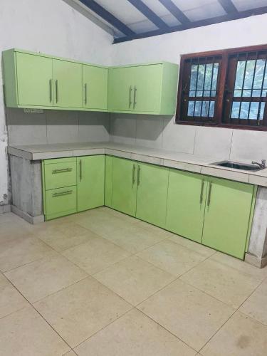 una cocina vacía con armarios verdes y una ventana en Jana Villa, en Kamburugamuwa
