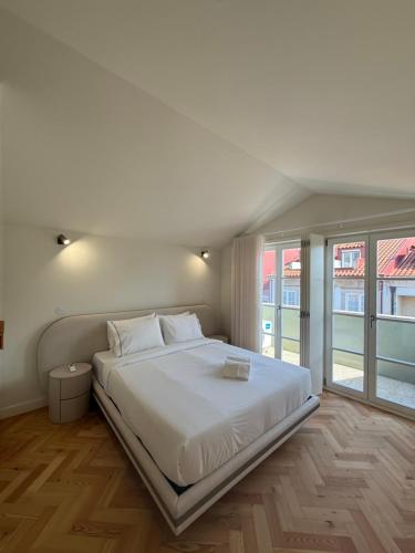 a white bedroom with a large white bed and windows at Luxury Duplex Apartment with terrace by Perpetual Relax in Braga