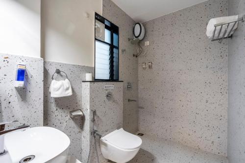 a bathroom with a toilet and a sink and a window at Candolim Pearl - Luxurious 1 BHK Apartment by SoCH Stays in Nerul