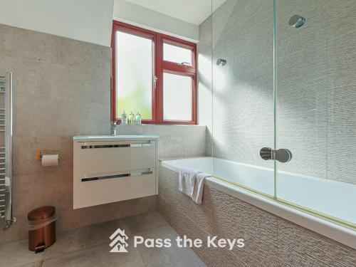 a bathroom with a tub and a sink and a shower at Pass the Keys Spacious Family Home - With Parking Garden in Maidenhead