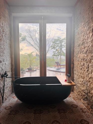 a large black bath tub in a room with a window at Bale Penida Villa in Nusa Penida