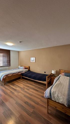 two beds in a room with wooden floors at Gästehaus Kaiser in Ostfildern