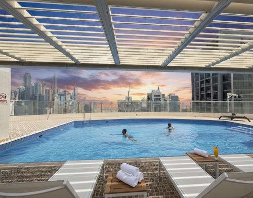 a large swimming pool with people in a city at Ultimate Stay - Modern 1BR with City View Rooftop Pool Access in Dubai