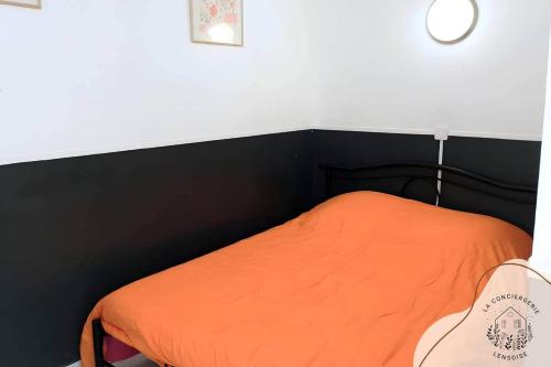 an orange bed with a black headboard in a room at Les appartements de Serge in Noeux-les-Mines