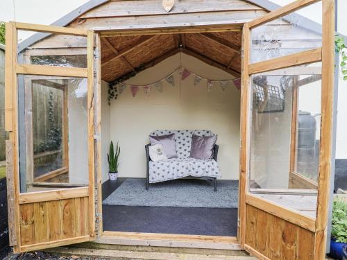 un gazebo en bois avec une chaise à l'intérieur dans l'établissement Rushmoor Cottage, à Colaton Raleigh