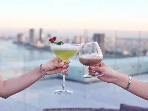 two people holding up two glasses of wine at Gold Apartment With Sea View In Da Nang Bay in Da Nang