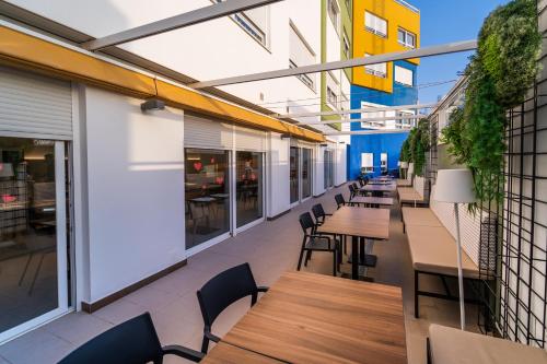 an outdoor patio with wooden tables and chairs at Vistamar Hotel Luxury Wellness By DLV -Adults Only- in Villajoyosa