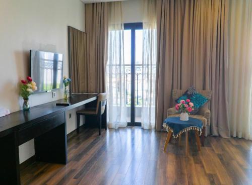 a living room with a desk and a table with flowers at Gold Apartment With Sea View In Da Nang Bay in Da Nang