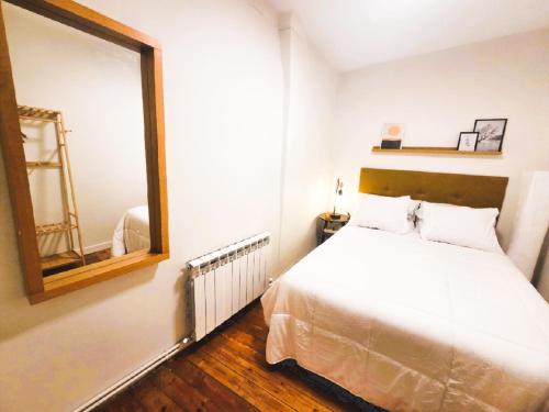 a bedroom with a white bed and a mirror at Apartamento Puerta Herradura, pleno centro Haro in Haro