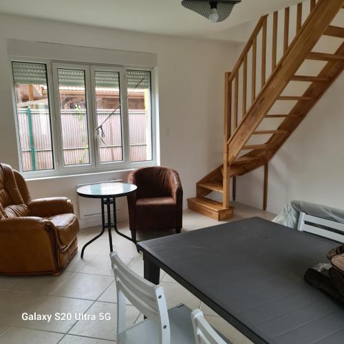 a living room with a table and chairs and a staircase at Maison typique picarde in Soissons