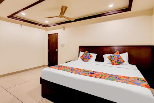 a bedroom with a large white bed with colorful pillows at FabHotel Alfa in Vijayawāda