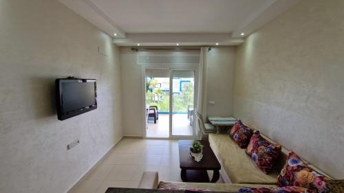 Una sala de estar con un sofá y un televisor en la pared. en Kariat Cabo, en Cabo Negro