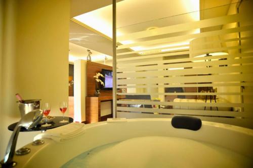 a bathroom with a tub and a table with wine glasses at Hotel Xperience in Jounieh