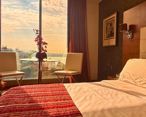a hotel room with a bed and a large window at Hotel Xperience in Jounieh