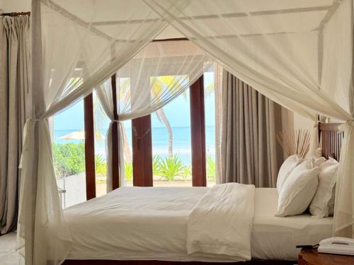 a bedroom with a white bed with a view of the ocean at Cardamon Hotel Nilaveli in Nilaveli