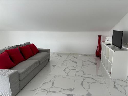 a living room with a gray couch and red pillows at In Barcelos View Lodge in Barcelos